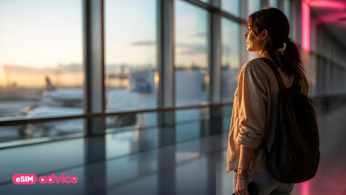 A traveller pausing in a sunlit airport terminal walkway at golden hour