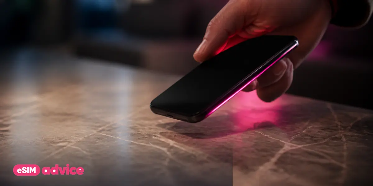 A hand lifting a phone from a marble surface with a magenta rim light