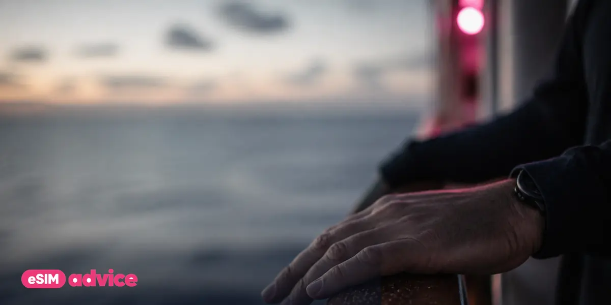A hand on a salt-flecked deck railing with ocean bokeh behind