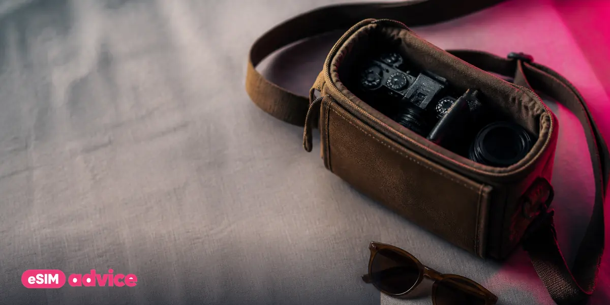 A small camera bag, sunglasses and a coiled cable on linen