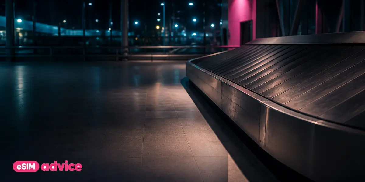 A baggage carousel hall at night with one overhead light on